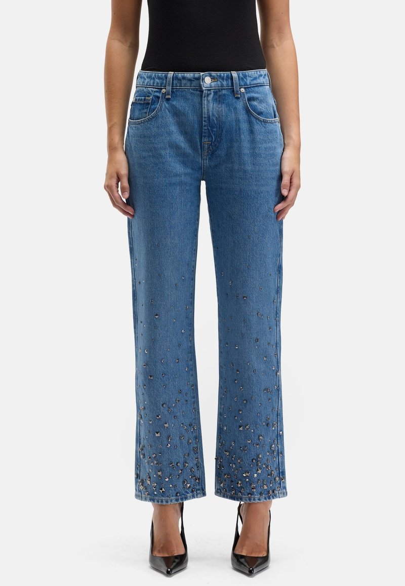 Jasnoniebieskie dżinsy z prostą nogawką, ozdobione metalicznymi elementami przy krawędzi. Posiadają przednie kieszenie oraz zapięcie na guzik.