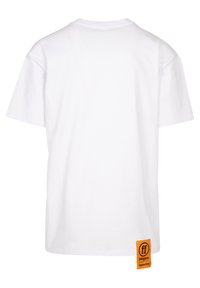 Balts īsām piedurknēm T-krekls ar apaļu apkakli un oranžu birku apakšējā labajā stūrī, uz kuras redzams zīmola logotips un teksts.