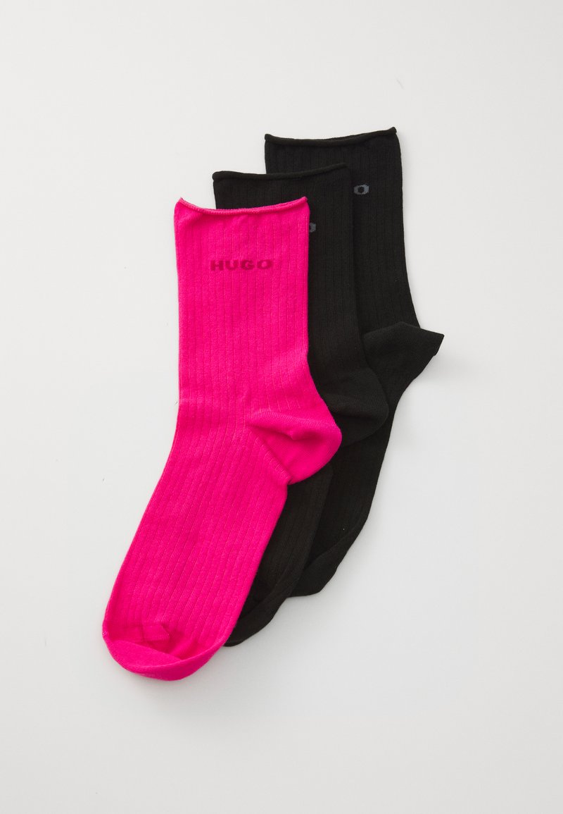 Tre par ribbede sokker: et par i lys pink med HUGO-logo, to sorte. Alle har midt-længer og en glat tekstur.