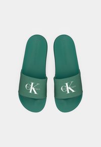 Infradito verde con soletta testurizzata. La fascia in tessuto presenta il logo bianco "CK" e la scritta "CALVIN KLEIN JEANS". Suola in gomma liscia.