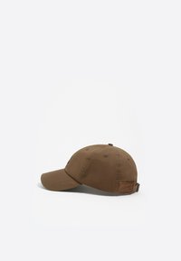 Gorra de béisbol de algodón marrón con visera curva, seis líneas de costura en la visera y una etiqueta de cuero rectangular en la parte trasera.