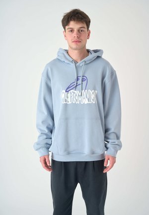 Light blue hoodie made of soft fabric, featuring a front kangaroo pocket and graphic print in purple and white. Paired with black pants.