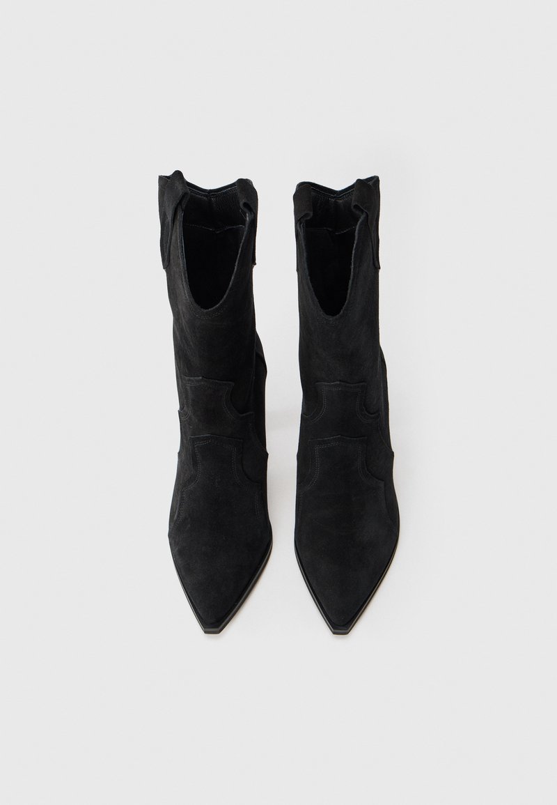 Stivaletti neri in suede con punta affusolata, caratterizzati da tagli laterali e una finitura opaca liscia. Tacco piatto per stabilità.