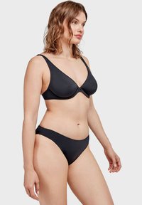 Completo bikini nero realizzato in un tessuto liscio e elastico. Il top ha spalline larghe e una forma triangolare, mentre il pantalone offre un taglio classico.