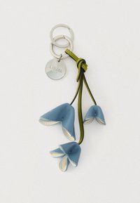 Nahkkast võtmehoidja, millel on kolm sinist lillekujulist pungat valge sisemise äärega, kinnitatud hõbedast metallrõngastele ja rohelisele nahkdetailile.