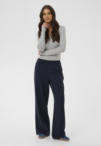 Gray ribbed long-sleeve top paired with high-waisted, wide-leg navy trousers. The outfit features a smooth texture and structured fit.