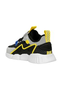 Czarne i szare siateczkowe sneakersy z żółtymi i niebieskimi akcentami, posiadające grubą białą podeszwę, regulowany pasek i paskowany uchwyt na pięcie.