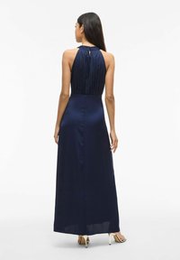 Granatowa satynowa sukienka maxi z wysokim kołnierzem, plisowanym gorsetem, odkrytymi plecami z detalem w kształcie kluczyka oraz dopasowanym fasonem sięgającym podłogi.