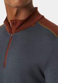 Grijze pullover met een kwart-rits kraag, voorzien van een donkerrode accent bij de nek en schouder, gestructureerde stof en subtiele stikdetails.