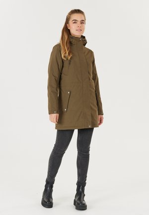 Olivengroene parka-jack, heuplengte met een hoge kraag, twee met rits gesloten zakken, drukknoopsluitingen aan de voorkant en een getextureerde stof. Gestyleerd met slanke grijze jeans en zwarte laarzen.
