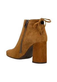 Stivali alla caviglia in suede marrone con tacco spesso, zip laterale e fiocco decorativo sul retro. Texture liscia con punta tonda.