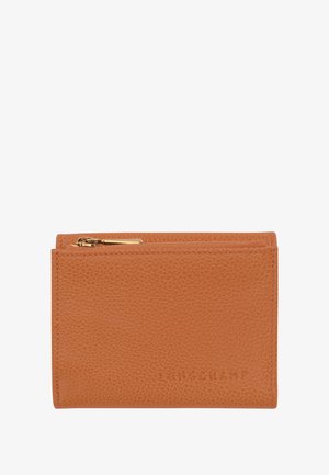 Tan leather wallet with a textured finish, featuring a zip closure and embossed logo detail on the front. Compact, rectangular design.