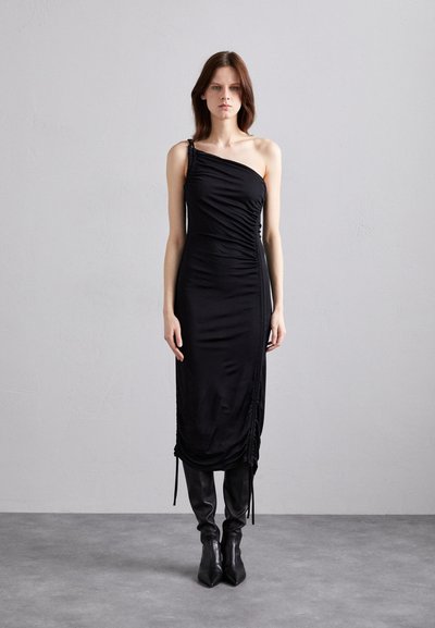 Rochie neagră, cu un umăr, dintr-o țesătură netedă, cu prindere pe laterale și detalii cu șnur. Modelul poartă cizme negre, cu vârful ascuțit.