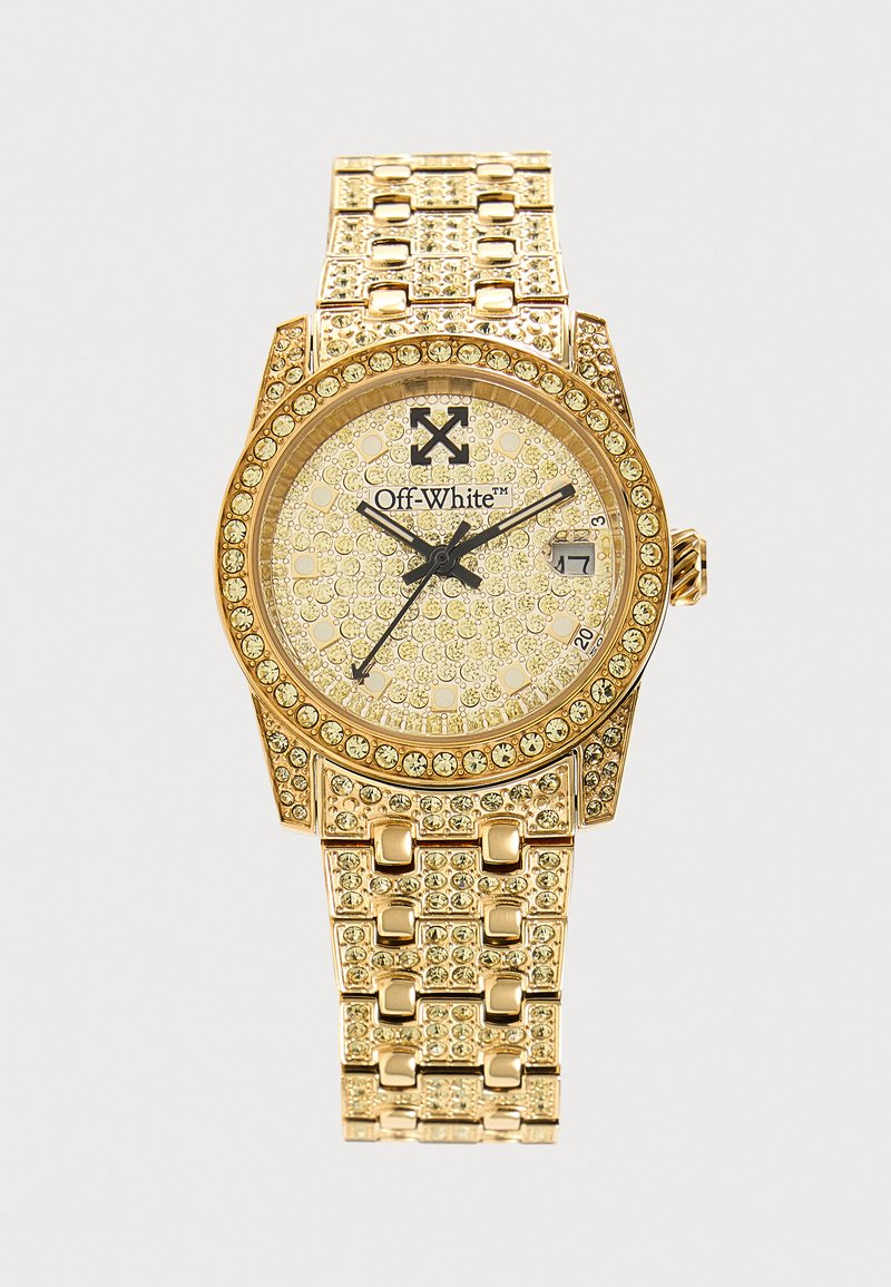 Montre en or avec un bracelet et un cadran ornés de cristaux, aiguilles noires, logo Off-White et affichage de la date indiquant le 17.