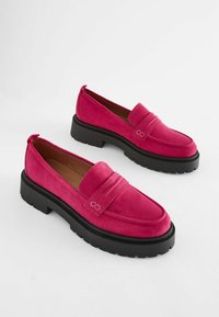 Loafers fucsia din suede, cu vârf rotund, linii decorative cusute și o talpă groasă din cauciuc negru. Toc întărit pentru o utilizare ușoară.