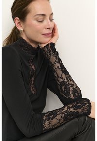 Black long-sleeve top featuring a lace high neckline and lace cuffs, with a form-fitting silhouette and smooth fabric texture.