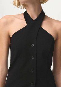 Black sleeveless top with a twisted neckline, featuring a fitted silhouette and six black buttons along the front for closure.