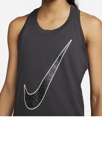 Schwarzes ärmelloses Tanktop mit einem großen, weiß umrandeten Nike-Swoosh, gefüllt mit einem schwarzen Leopardenmuster. Glatte Baumwollstruktur.