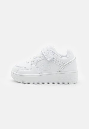 White athletic sneaker with a smooth leather upper, perforated toe, Velcro strap, textured sole, and embossed logo details.