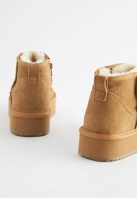 PRUUNIST VALGESTE KARUSNAHKIDEGA ANKLE-BOOTSID, LAMEAD PÕHI JA DEKORATIIVSED TAGATABID. DISAINIL ON NÕMALDÕMBED JA STRUKTUURIKAD PINNAD.