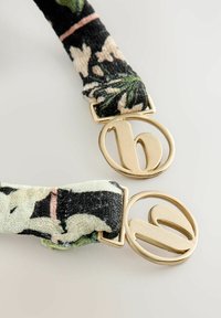 Bloemmotief stoffen banden in zwart, roomkleur en groen, met goudkleurige, ronde hardware met een logo-accent aan elk uiteinde.