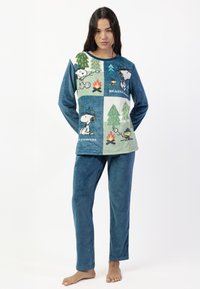 Conjunto de pijama de forro polar que incluye una parte superior azul con gráficos de Snoopy, patrones verdes y azules, y pantalones azules lisos, todo en una textura suave y tersa.