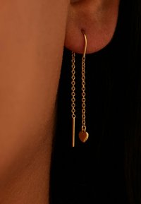 Gold dangling earrings featuring two chains: one with a straight bar and the other with a heart charm, showcasing a smooth finish.