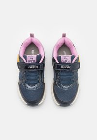 Baskets bleues avec une tige en tissu texturé, doublure rose et accents noirs. Elles présentent une sangle en velcro et une semelle blanche épaisse.