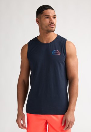 Débardeur en coton bleu marine avec un col arrondi et des emmanchures. Présente un logo coloré sur la partie gauche de la poitrine. Texture lisse.