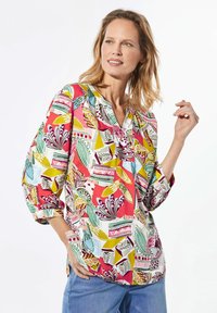 Mehrfarbige, gemusterte Bluse mit lockerer Passform, die florale und geometrische Designs in Pink, Grün und Blau auf einem weißen Hintergrund zeigt.
