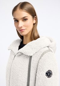 Lichtgrijze fleece jas met een ritssluiting, een capuchon en grijze accenten. Heeft een gestructureerd oppervlak en een logodetail op de mouw.