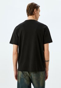 Zwarte katoenen t-shirt met korte mouwen en een ronde halslijn, met een relaxte pasvorm en een soepele textuur. Zichtbare stikseldetails.
