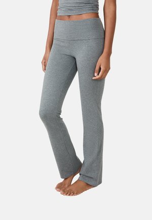 Pantalons de sport gris évasés en tissu doux et extensible. Dotés d'une taille haute et de coutures latérales pour une silhouette ajustée mais confortable.