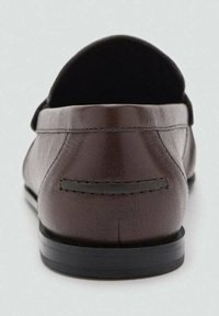 Mocasines de cuero marrón con una textura suave, parte trasera redondeada, suela negra y un sutil detalle de costura. Sin herrajes o acentos visibles.