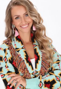 Cardigan lavorato a maglia con base turchese e motivi geometrici rossi, gialli e neri, impreziosito da dettagli in frange lungo il colletto.