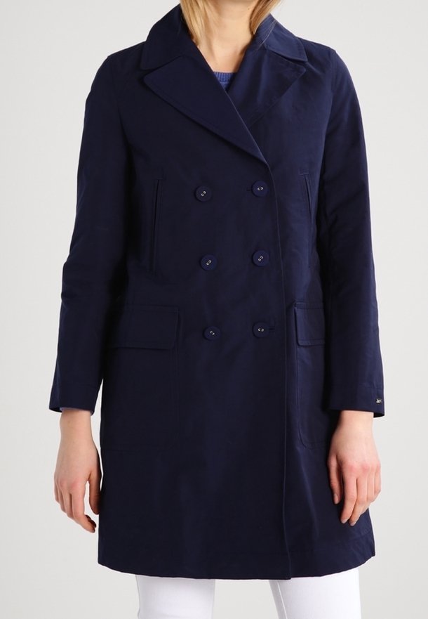 Manteau croisé bleu marine avec gros boutons, deux poches avant, col à revers à pointe et manches longues, fabriqué en tissu lisse.