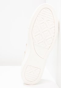 Baskets blanches avec semelle en caoutchouc texturé, dotées d'un motif en diamant et d'une touche de logo, tige en toile légère avec un design minimaliste.