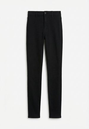 Μαύρο στενό τζιν με ψηλή μέση, θηλιές για ζώνη, κουμπί μπροστά και κλείσιμο με φερμουάρ, απλωμένο επίπεδα σε λευκό φόντο.