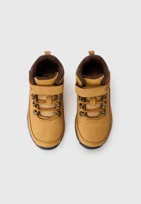 Botas de senderismo de piel marrón con un diseño de cordones, ojales de metal, correa de velcro y suela de goma texturizada. Presenta soporte acolchado para el tobillo.
