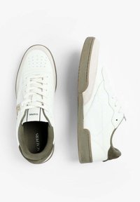 Un par de zapatillas blancas de caña baja con acentos grises y suelas texturizadas, una mostrando la vista superior y la otra la vista lateral sobre un fondo blanco.