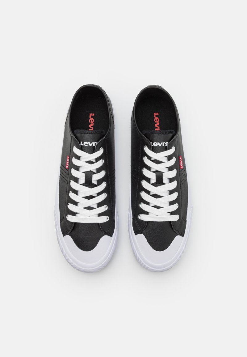 Zapatillas negras con cordones blancos y suelas de goma blancas. Diseño de cuero texturizado con el logo de Levi's en rojo en el lateral y en la lengüeta.