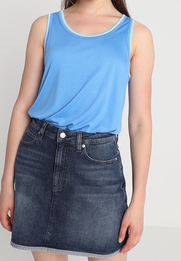 Ljusblå ärmlös topp med en kontrasterande halsringning, parat med en mörk denim mini kjol med framfickor och en råkant.