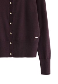 Bordeaux strikket cardigan med knapfortsats, ribbede manchetter og kant, samt en lille metallisk detalje ved bunden.