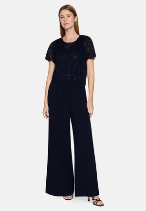 Navy lace cropped top with short sleeves, paired with wide-leg navy trousers. The outfit features a subtle sheen and delicate detailing.