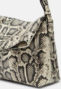 Borsa a tracolla con motivo serpente in nero e crema, caratterizzata da una finitura in pelle texture, una silhouette morbida e una tracolla regolabile.