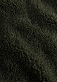 Tejido de forro polar verde oscuro con una superficie suave y esponjosa, y fibras elevadas, creando una apariencia cálida y acogedora.