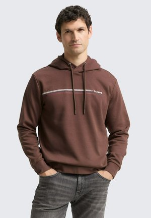 Brauner Hoodie mit Kordeln, der weiße und rote horizontale Streifen über die Brust hat. Glatte Textur, lockere Passform und Kängurutasche.