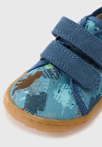 Modrá plátená obuv s dvoma suchými zipsami. Má vzorovaný zvršok s rôznorodými farebnými motívmi. Gumená podrážka pre lepšiu priľnavosť a odolnosť.