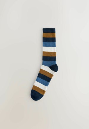 Stribede sokker i mørk navy, blå, brun og hvid. Fremstillet af blødt stof med en ribbet kant, der har hærdende vandrette bånd.