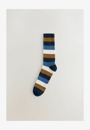 Stribede sokker i mørk navy, blå, brun og hvid. Fremstillet af blødt stof med en ribbet kant, der har hærdende vandrette bånd.